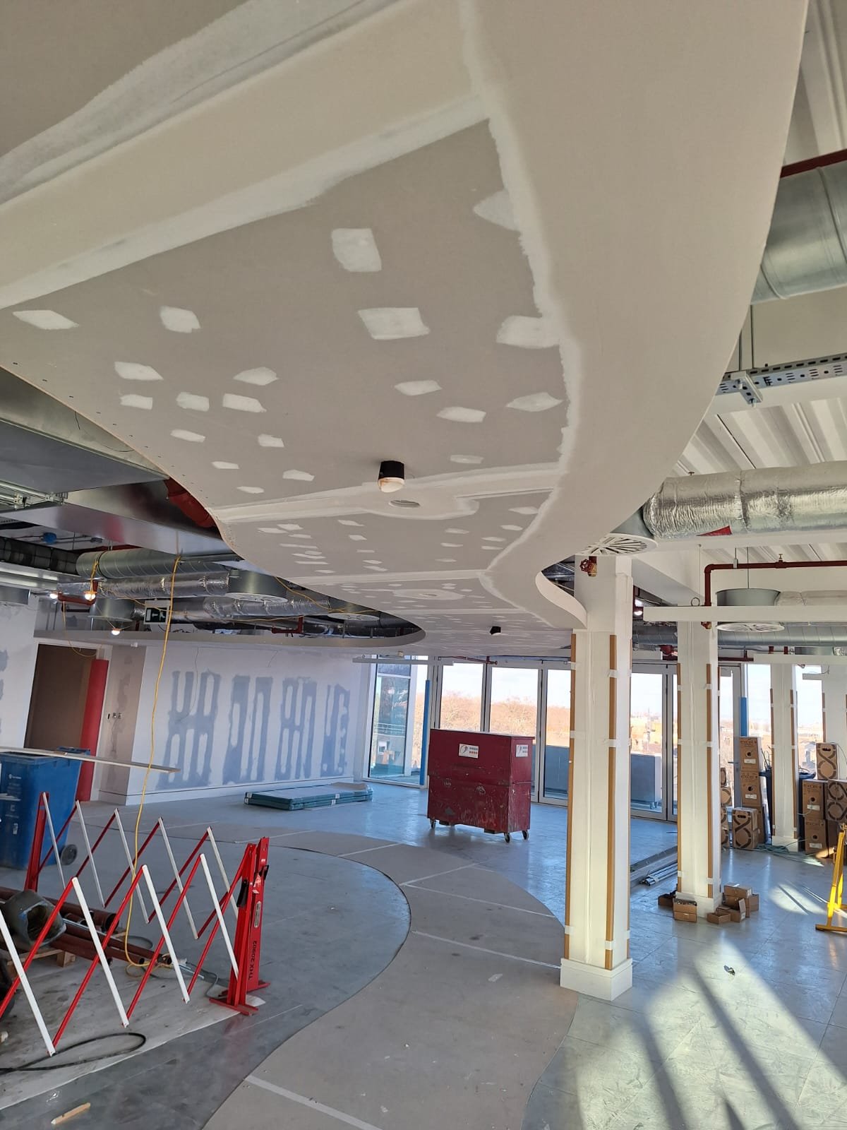 Wide view of an office floor mid fit-out with plasterboard ceilings being jointed